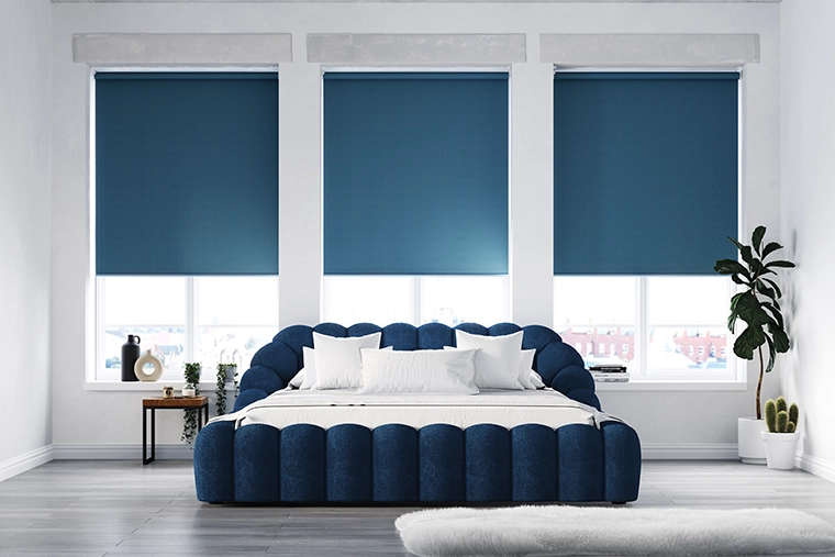 Set of deep blue roller blinds from illumin8 in a bedroom