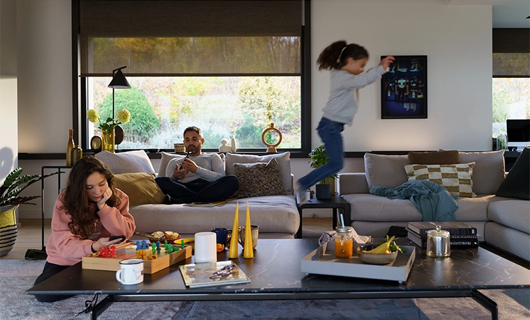 Family spending time together in a lounge when a father is closing the electric blinds